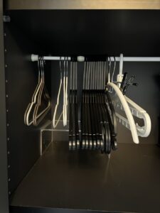 リビング収納に突っ張り棒を取り付けハンガーを収納している写真